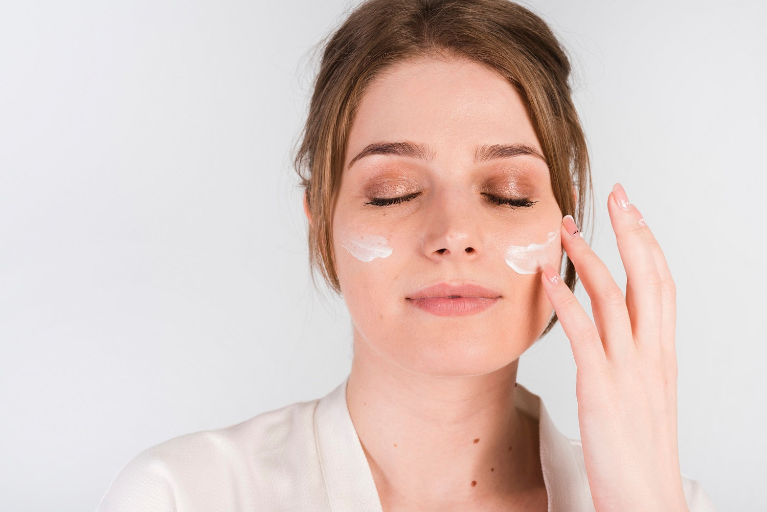 Woman applying Dead Sea mineral face cream with glowing skin